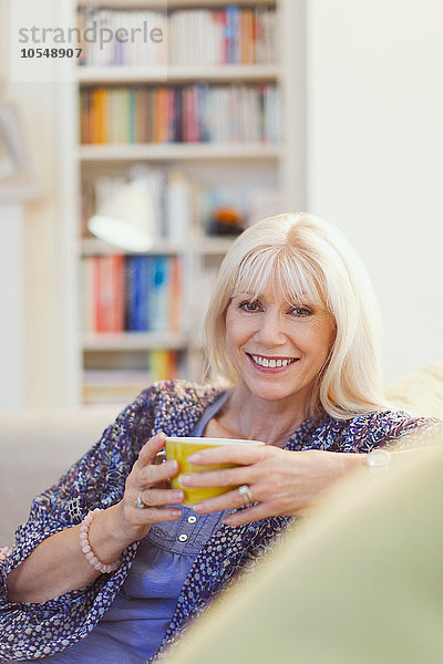 Portrait lächelnde Seniorin beim Kaffeetrinken auf dem Sofa