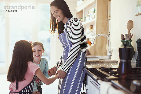 Mutter und Töchter halten Händchen in der Küche