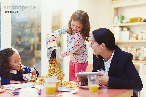 Mädchen  die viel Müsli am Frühstückstisch ausschenken