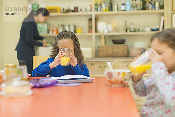 Mädchen trinken Orangensaft am Frühstückstisch