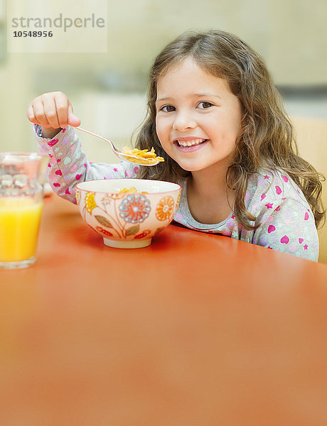 Portrait lächelndes Mädchen isst Müsli am Frühstückstisch