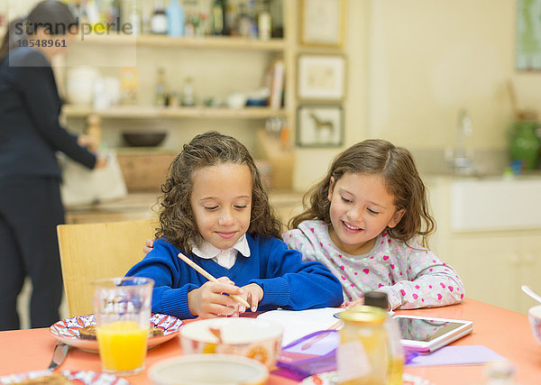 Mädchen machen Hausaufgaben am Frühstückstisch