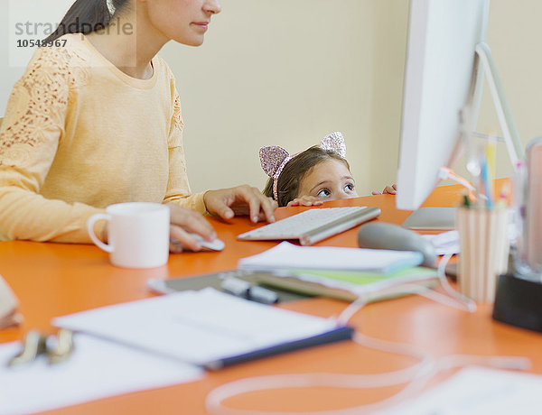 Mädchen in Mausohren Stirnband beobachtende Mutter bei der Arbeit am Computer