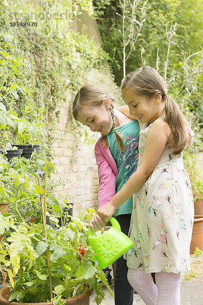 Mädchen gießen Pflanzen im Garten