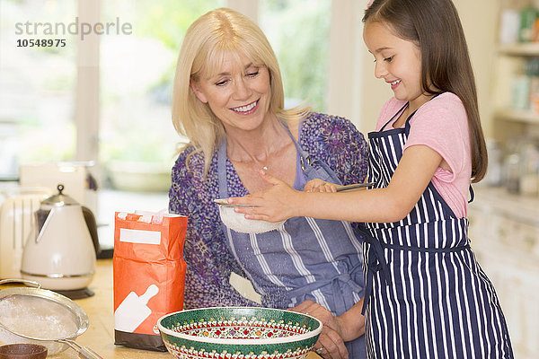 Großmutter und Enkelin beim Backen von Mehl in der Küche