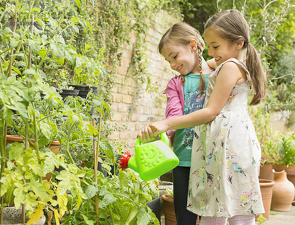 Umarmung von Mädchen beim Gießen von Pflanzen im Garten