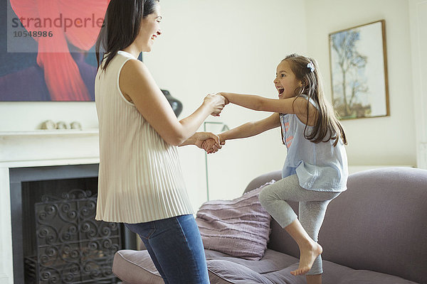 Verspielte Mutter und Tochter tanzen im Wohnzimmer