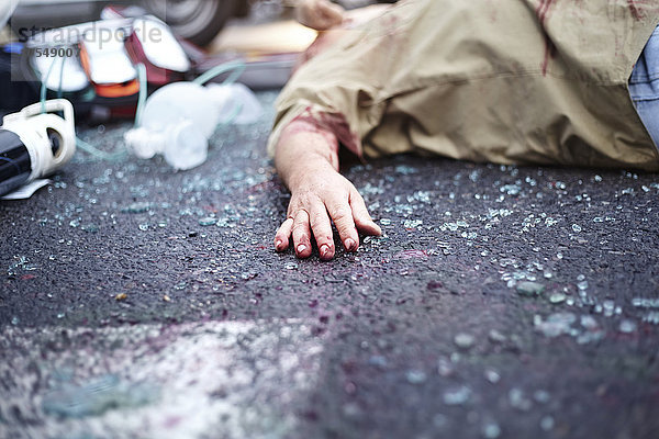 Blutige Hand des Autounfallopfers auf der Straße zwischen zerbrochenem Glas