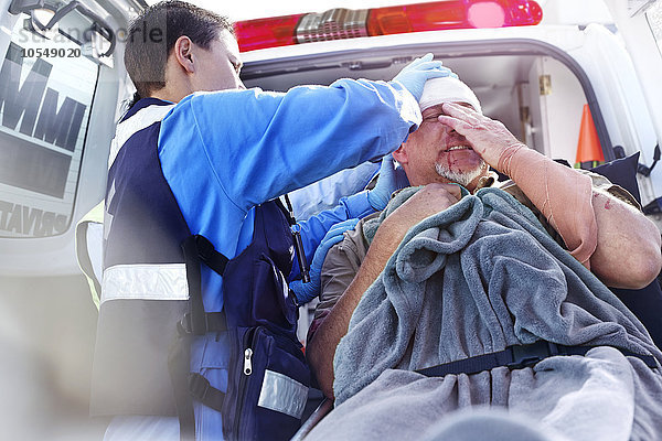 Rettungshelfer  der sich um den Patienten hinten im Krankenwagen kümmert.