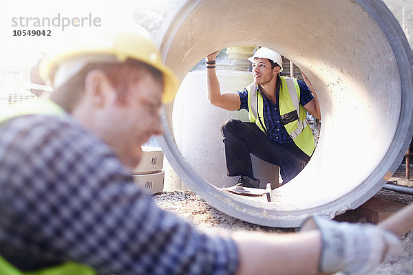 Bauarbeiter bei der Untersuchung von Betonrohren