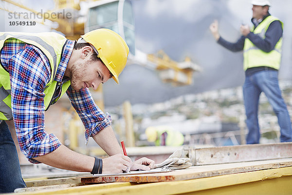 Bauarbeiter schreiben auf der Baustelle auf die Zwischenablage