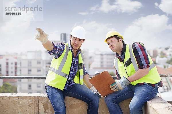 Bauarbeiter und Ingenieur mit Zwischenablage auf der Hochbaustelle