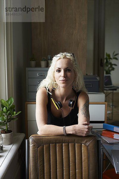 Portrait selbstbewusste junge Frau mit Kopfhörer und Tattoo im Home Office
