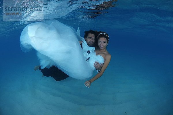 Bräutigam hält seine Braut in den Armen  unter Wasser  Indischer Ozean  Malediven  Asien