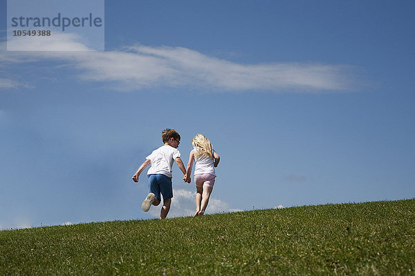 Zwei Kinder rennen auf einen Hügel