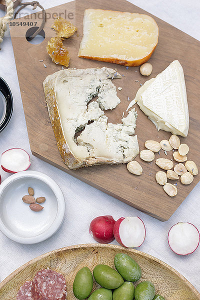 Hochwinkelansicht einer Käseplatte  Käse  Oliven  Nüsse und Radieschen auf einem Tisch.