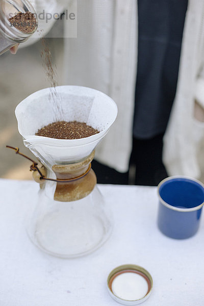 Hochwinkelansicht einer Glas-Kaffeemaschine  einer konischen Dose mit Filterpapier und Kaffeesatz.