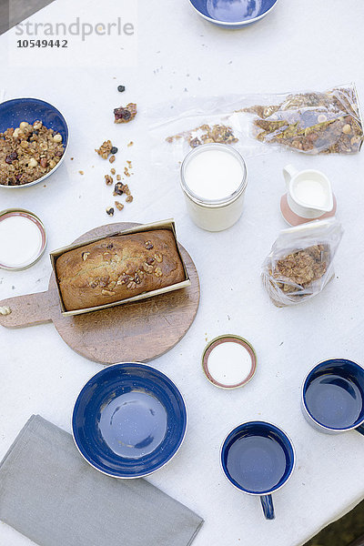 Hochwinkelansicht eines Tisches mit Bechern und Schalen  einem Kuchen und Müsli.