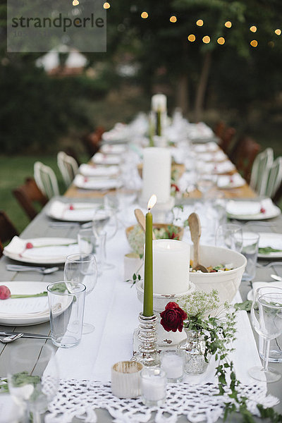 Langer  mit Tellern und Gläsern gedeckter Tisch  Essen und Trinken in einem Garten.