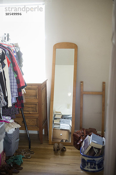 Spiegel  Kommode  Kleiderständer und Schuhe in einem Schlafzimmer.