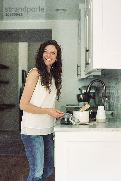 Frau  die in einer Küche steht und eine Kanne Tee zubereitet.