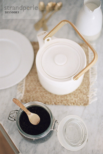Hochwinkelansicht einer Teekanne und eines Glasgefäßes mit Teeblättern.