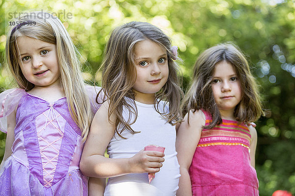 Drei lächelnde junge Mädchen bei einer Gartenparty.