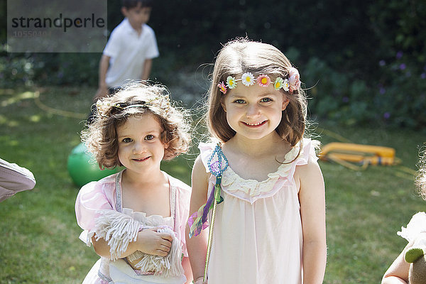 Zwei lächelnde junge Mädchen bei einer Gartenparty.