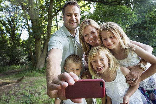 Familie mit drei Kindern  die ein Selfie nimmt.