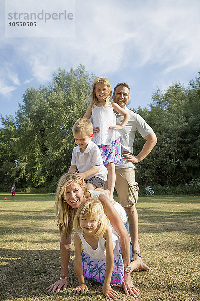 Familie mit drei Kindern  die in einem Park spielen.