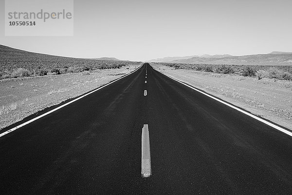 Eine schwarze obere Straße mit einer zentralen Linie  die in die Ferne  die Straße vor uns  reicht.