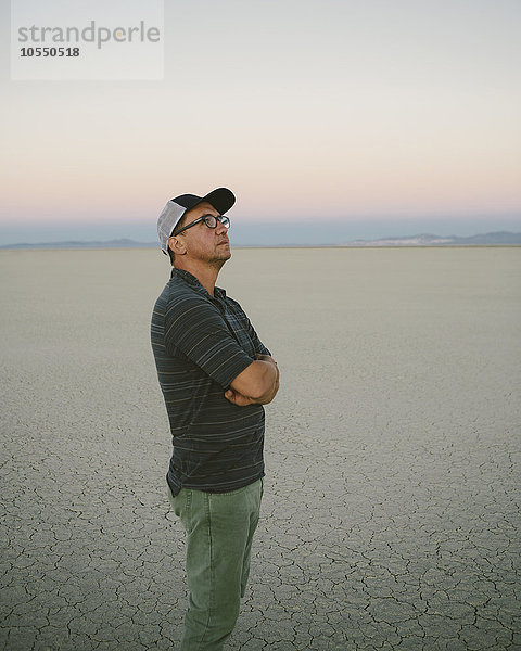 Ein Mann mittleren Alters  der in der Morgendämmerung in der Black-Rock-Wüste den Blick auf sich nimmt und sich umsieht