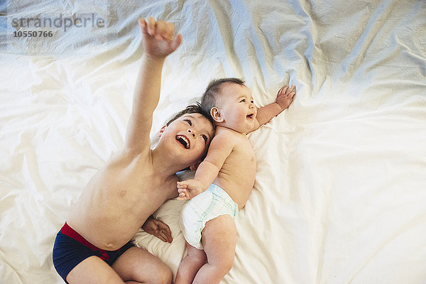 Zwei Kinder  ein Bruder und eine kleine Schwester liegend und spielen zusammen.