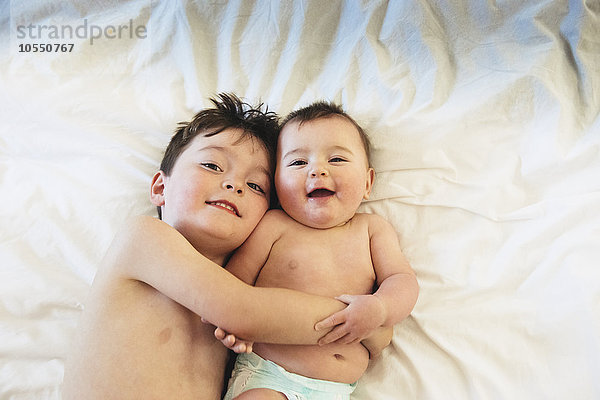 Zwei Kinder  ein Bruder und eine kleine Schwester liegend und spielen zusammen.