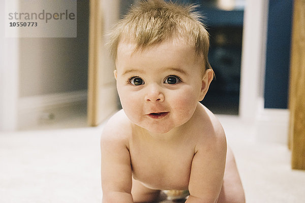 Ein kleines Baby krabbelt auf einem Teppich.