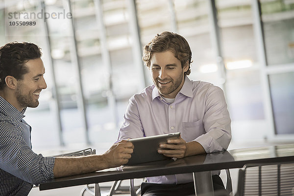 Zwei Männer schauen auf einen digitalen Tablet-Bildschirm.