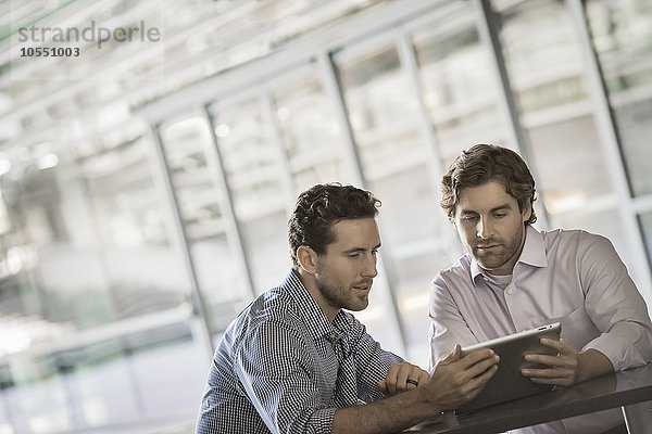 Zwei Männer schauen auf einen digitalen Tablet-Bildschirm.