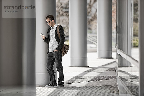Ein Mann vor einem Gebäude  der sein Smartphone überprüft.
