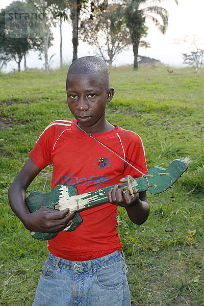 Junge spielt  musiziert auf selbst gebauter Gitarre  Matamba-Solo  Provinz Bandundu  Republik Kongo
