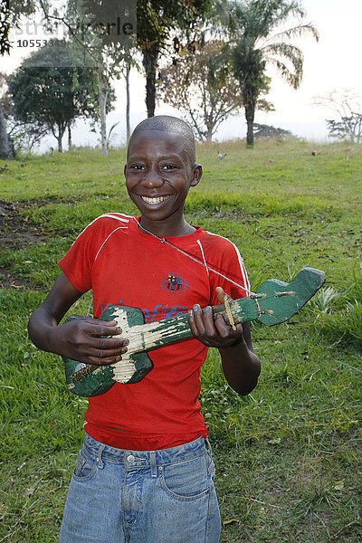 Lachender  fröhlicher Junge musiziert  spielt auf selbst gebauter Gitarre  Matamba-Solo  Provinz Bandundu  Republik Kongo