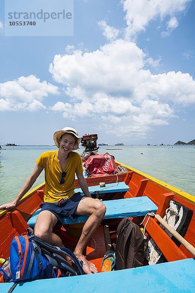 Junger Mann sitzt in einem Longtail-Boot  türkises Meer  Insel Koh Tao  Golf von Thailand  Thailand  Asien