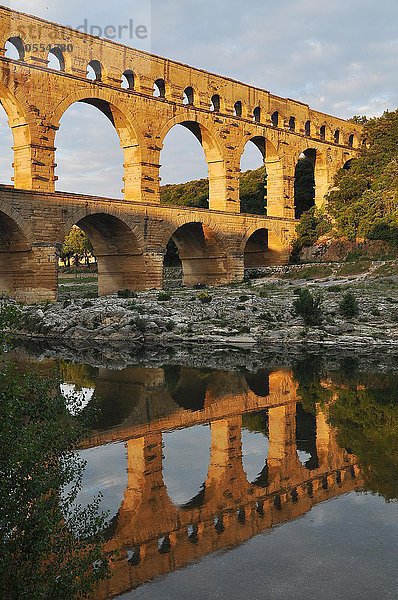 Römisches Aquädukt Pont du Gard spiegelt sich im Gardon Fluss am Abend  Remoulins  Provence  Südfrankreich  Frankreich  Europa