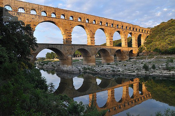 Römisches Aquädukt Pont du Gard spiegelt sich im Gardon Fluss am Abend  Remoulins  Provence  Südfrankreich  Frankreich  Europa