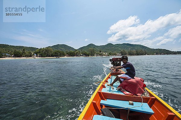 Einheimischer Mann sitzt am Heck und steuert ein Longtail-Boot im Meer  Insel Koh Tao  Golf von Thailand  Thailand  Asien