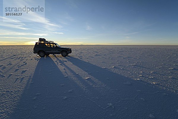 Geländewagen mit Schatten zum Sonnenaufgang auf Salzsee  Salar de Uyuni  Bolivien  Südamerika