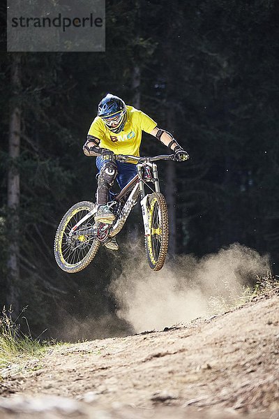 Mountainbiker  Downhill Biker springt bei einer Kante in einem Downhilltrail  Mutterer Alm  Muttereralmpark  Mutters  Innsbruck  Tirol  Österreich  Europa