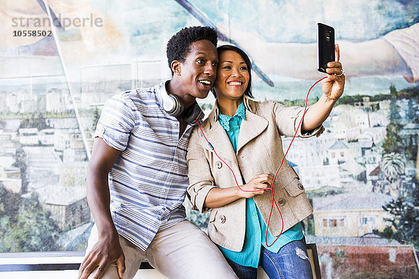 Pärchen macht Selfie mit digitalem Tablet vor Wandmalerei