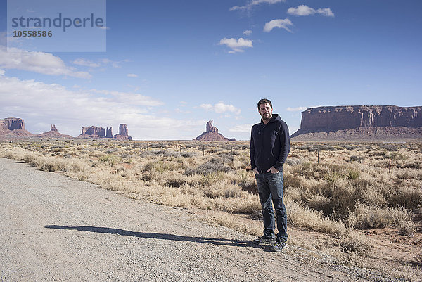 Kaukasischer Mann steht auf einer unbefestigten Straße in der Wüste