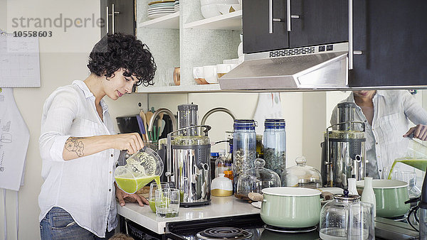 Kaukasische Frau gießt Saft in der Küche ein