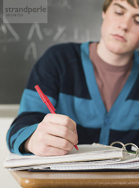 Schüler schreibt Notizen am Schreibtisch im Klassenzimmer